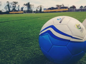 A close-up picture of the game ball on the Adelphi soccer field. 